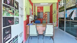 A room with a desk, two chairs, a fan, and various posters on the walls. - Oyo 90640 D'village River & Cafe Chalet (Kuala Tembeling)