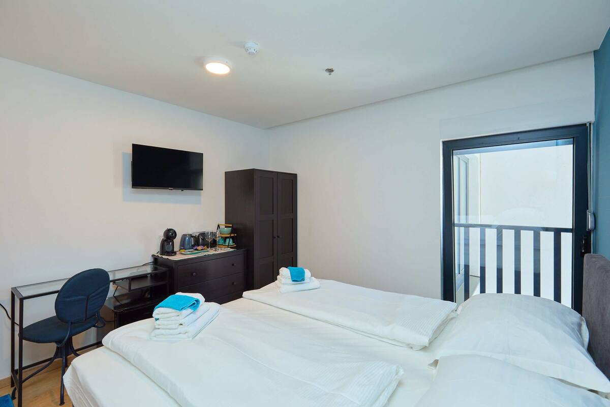 A hotel room with two beds, a desk, a chair, a wardrobe, and a TV.
