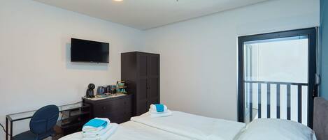 A hotel room with two beds, a desk, a chair, a wardrobe, and a TV.