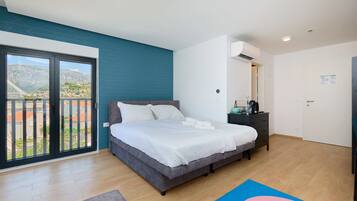 Un dormitorio con cama, mesita de noche, cómoda, ventana con vistas y puerta.