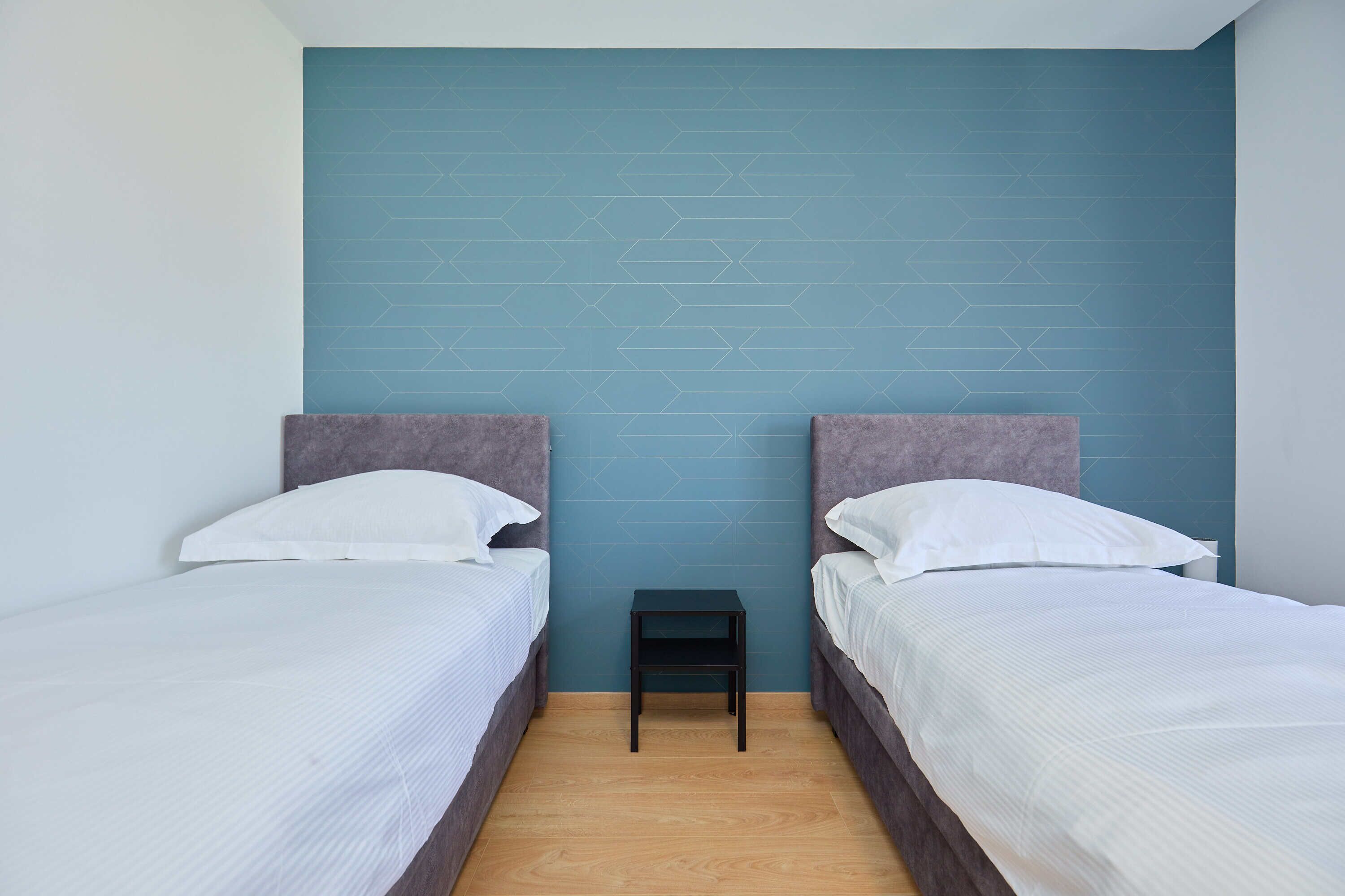 Habitación con dos camas, cada una con cabecero y ropa de cama blanca.
