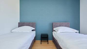 Habitación con dos camas, cada una con cabecero y ropa de cama blanca.