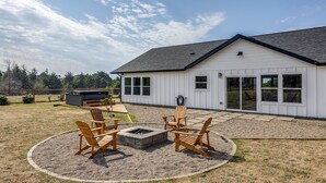 Una casa con porche cubierto, mobiliario exterior y una chimenea.