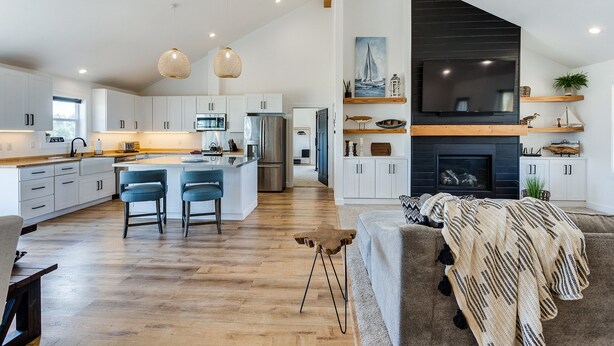 Una cocina moderna con armarios blancos, una isla central y lámparas colgantes de mimbre.