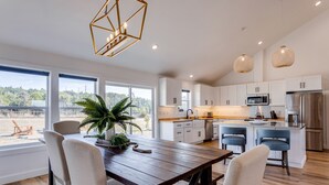 Una cocina moderna con gabinetes blancos, electrodomésticos de acero inoxidable y una isla grande con taburetes de bar.