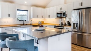 Una cocina moderna con armarios blancos, electrodomésticos de acero inoxidable y una isla central con asientos.