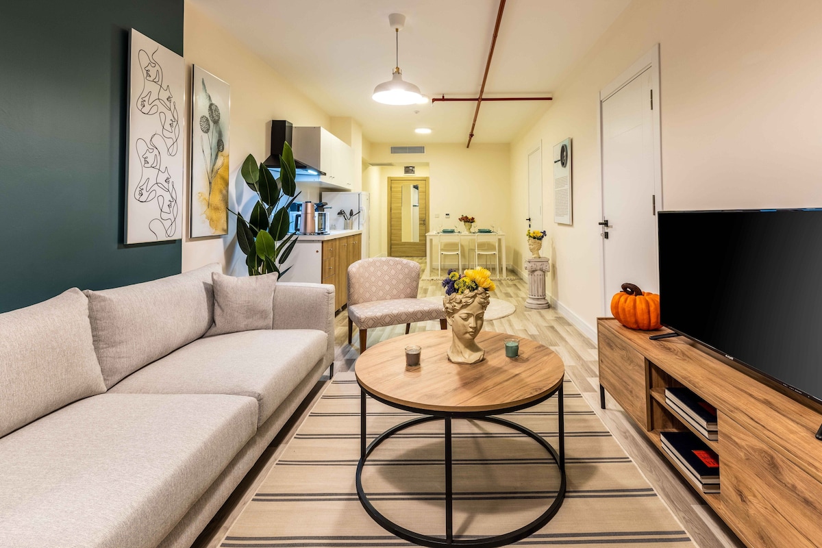 Un salon comprenant un canapé, une table basse, un téléviseur et un coin repas avec des chaises et une table.