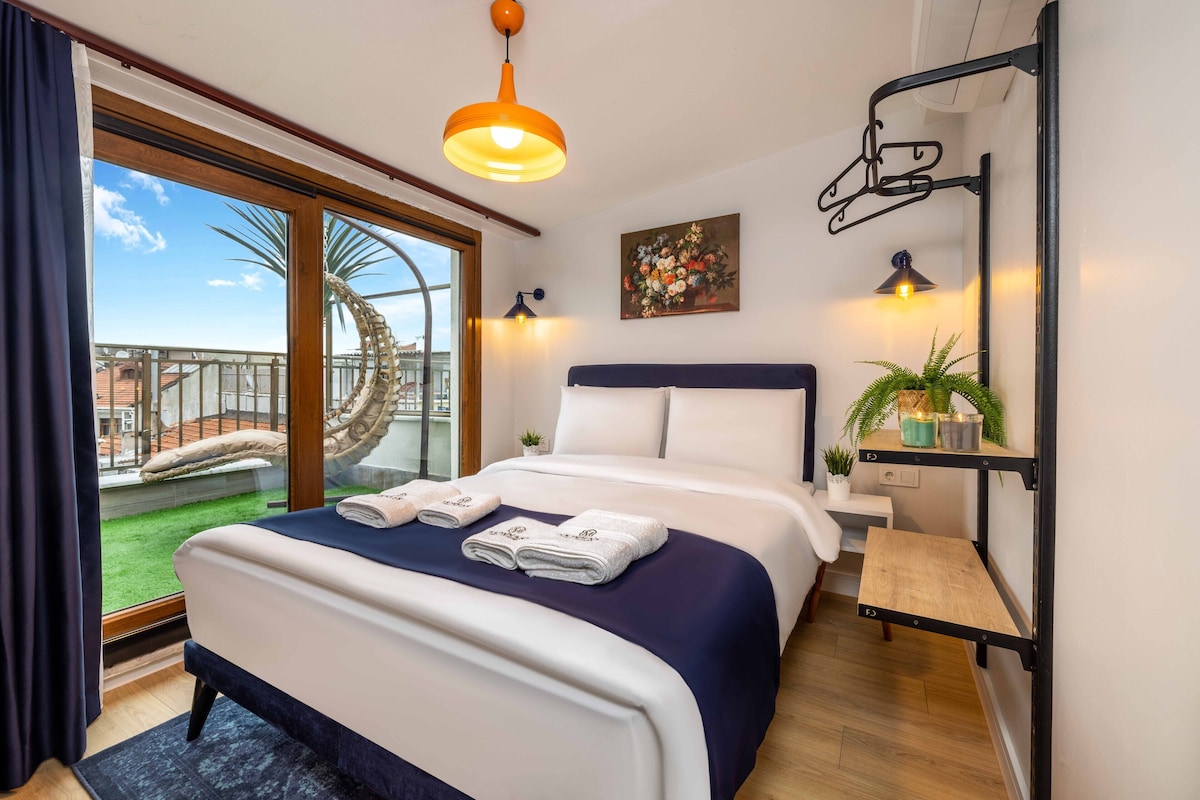 Une chambre d’hôtel avec un grand lit, un balcon avec vue, un petit bureau et une plante en pot.