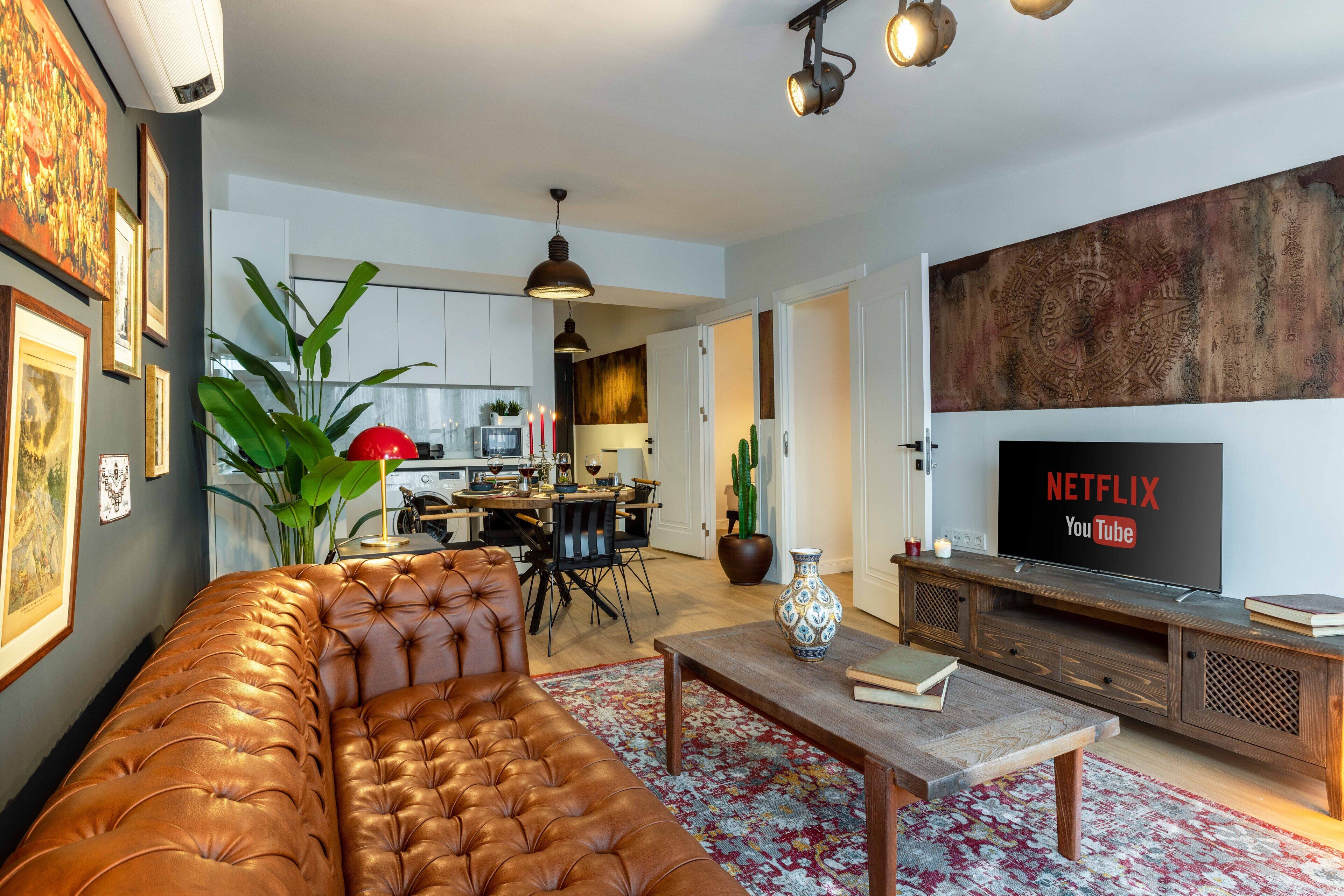 A modern living room with a leather sofa, a wooden coffee table, and a TV displaying Netflix and YouTube logos.