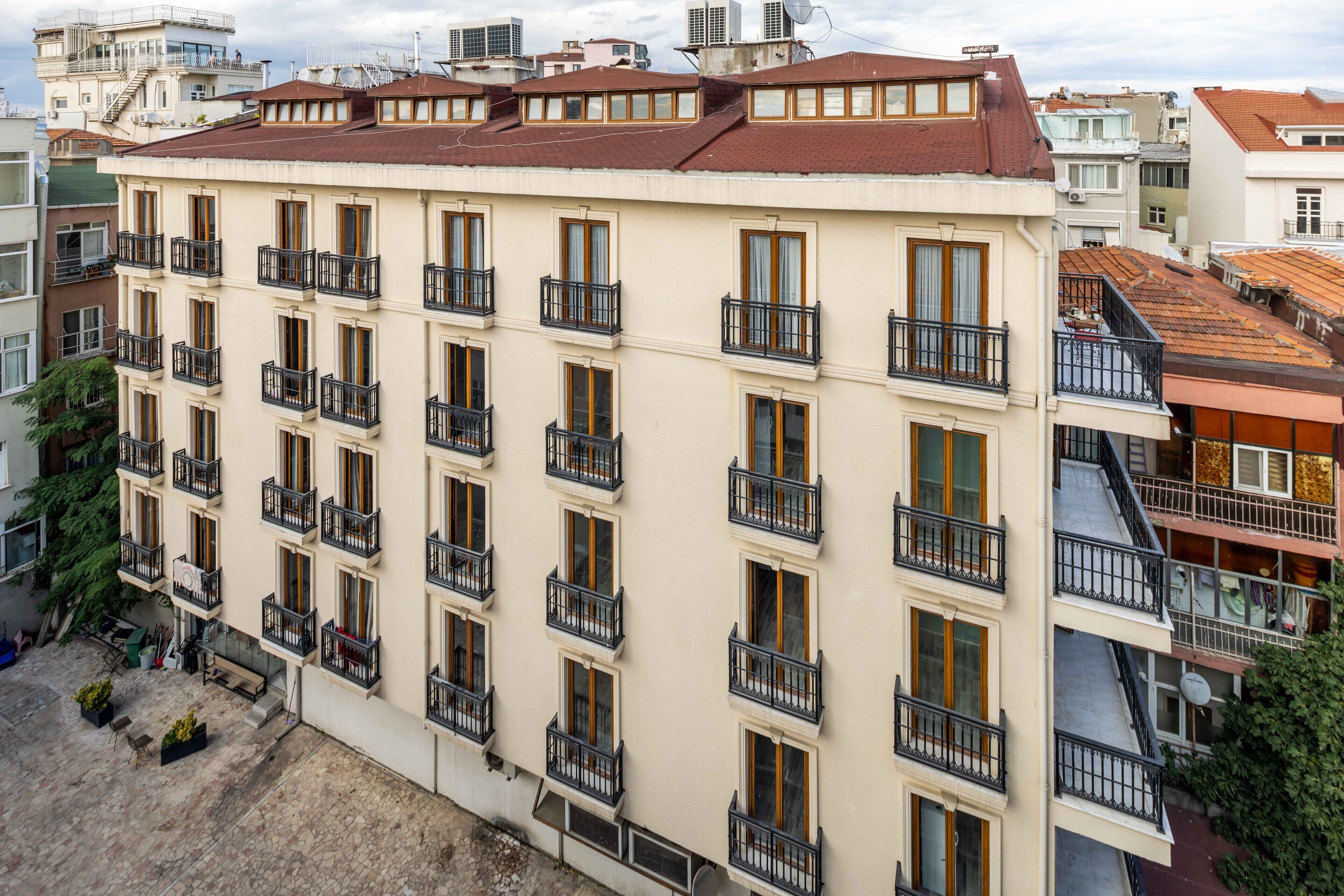 Ein mehrstöckiges Hotel mit Balkonen, einem gepflasterten Innenhof und angrenzenden Gebäuden.