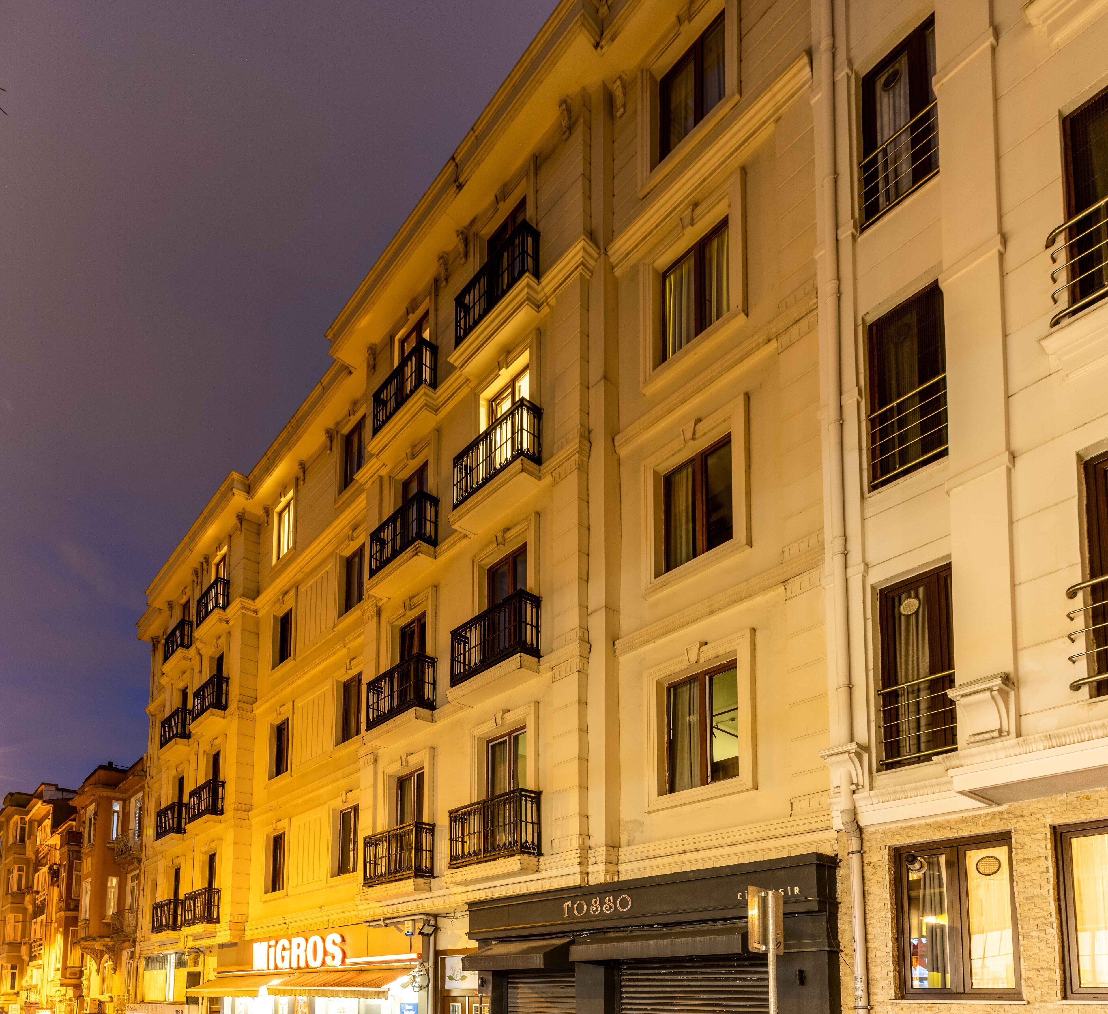 A multi-story building with balconies and large windows, featuring storefronts with signage.