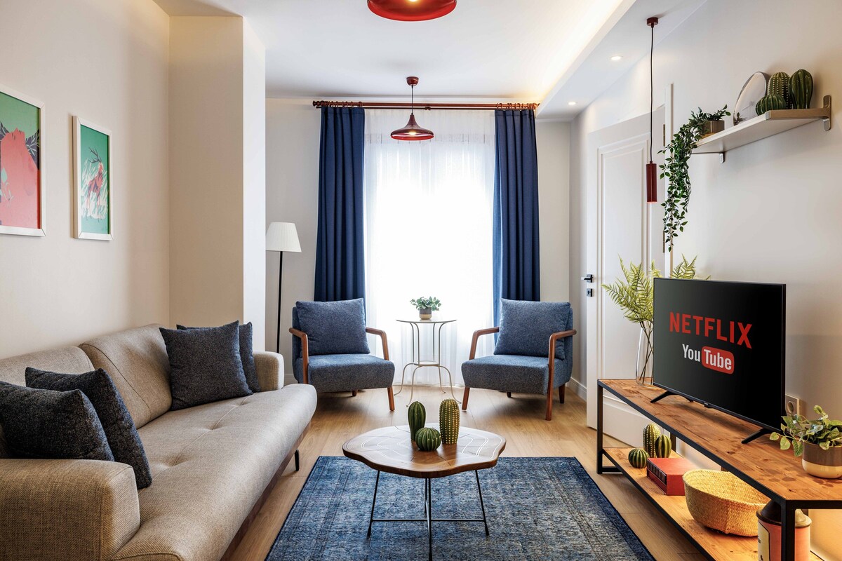 Un salon moderne comprenant un canapé, deux fauteuils, une table basse et un téléviseur affichant les logos de Netflix et YouTube.