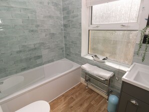 Ein Badezimmer mit Badewanne, Waschbecken und einem Fenster mit Blick nach außen.