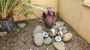Een tuin met een decoratieve drakenstandbeeld, een potplant en verschillende bolvormige spiegels.