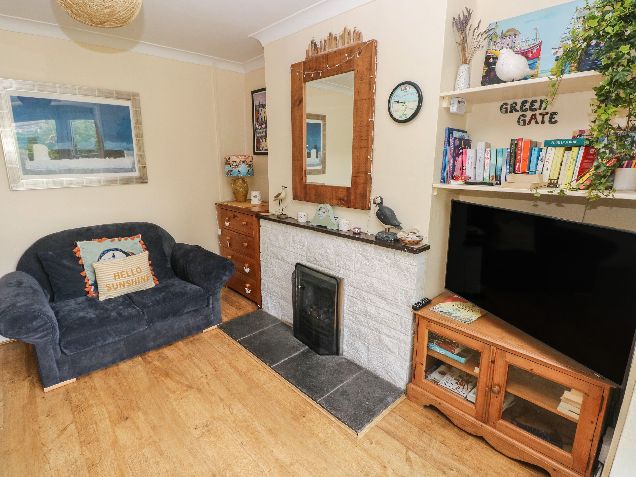A living room with a dark blue sofa, a fireplace, a television, and a bookshelf with books.