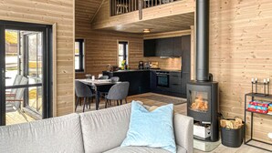 Un interior de cabaña acogedor con sofá, comedor, cocina y estufa de leña.