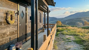 Una cabaña de madera con un balcón de madera y vistas a las montañas.