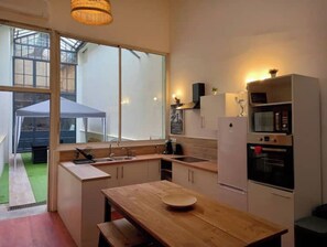 Une cuisine moderne avec une table en bois, des armoires blanches et une grande fenêtre.