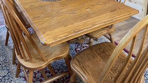 A wooden dining table with chairs, a vase, and a staircase in the background. - The Woolybugger Barn (Cameron)