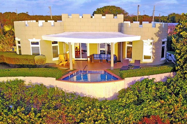 Un bâtiment qui ressemble à un château, doté d’une piscine, d’un patio couvert et d’un jardin.