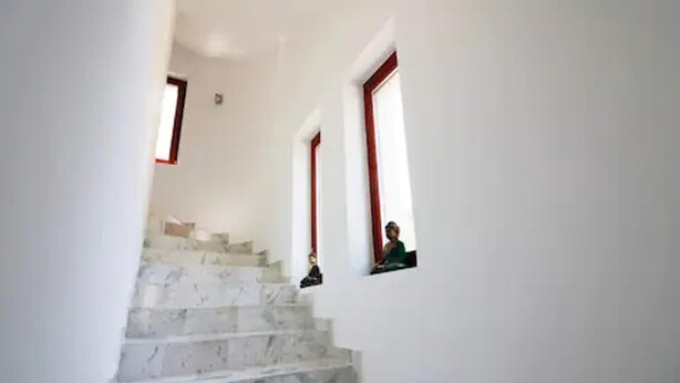 Una escalera con paredes blancas y marcos de ventana rojos.