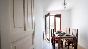 Un comedor con una mesa y sillas de madera, un candelabro y vistas a través de un ventanal abierto.