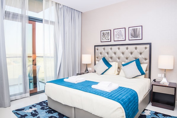 A hotel room with a large bed, two bedside tables, a window with curtains, and three framed pictures on the wall.