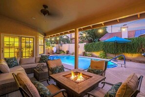 A covered outdoor area with a pool, seating, and a fire pit.