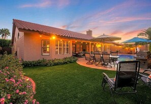 A house with a patio, outdoor seating, and a pool.