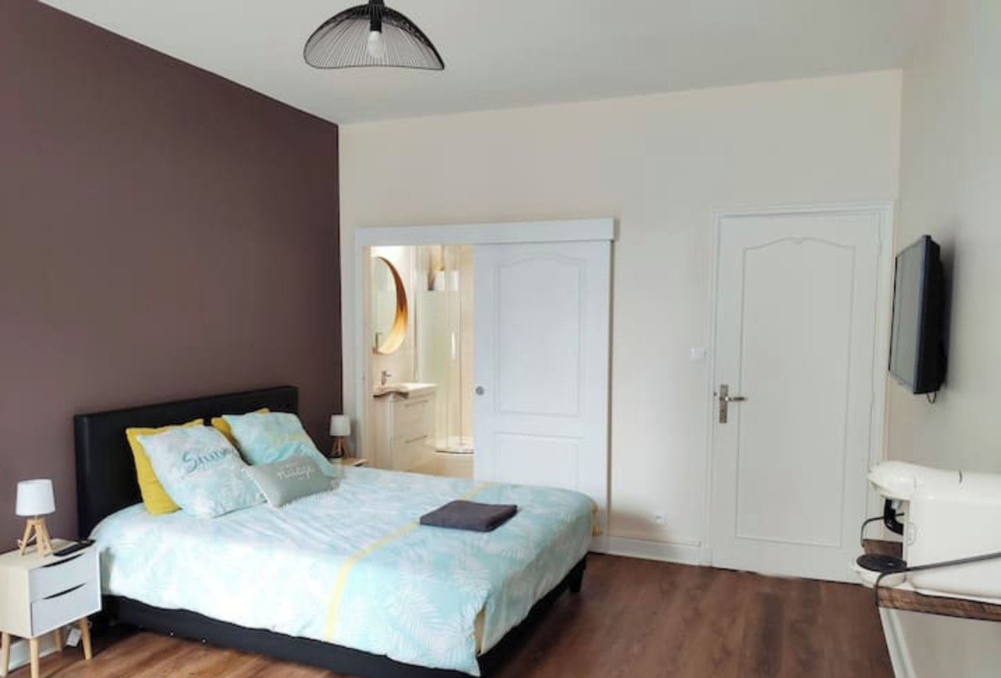 Een slaapkamer met een bed, nachtkastjes, een kledingkast en een televisie.