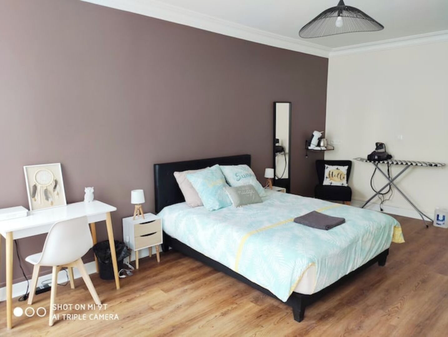 Ein Schlafzimmer mit Bett, Nachttisch, Lampe und Schreibtisch mit Stuhl.