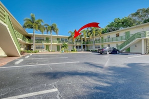 A hotel with a parking lot, multiple-story buildings, and palm trees.
