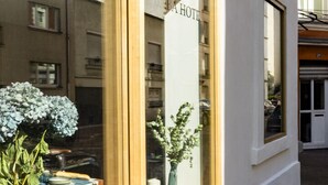 Fachada de hotel com grandes janelas, estrutura de madeira e uma placa com a inscrição 'BETA HOTEL'.
