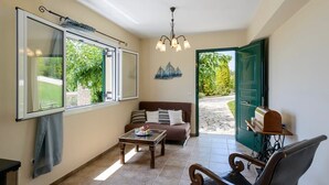 Une pièce confortable avec un canapé, une table basse, un fauteuil et une grande fenêtre avec des rideaux.