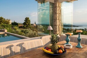 A poolside table with fruit and a lamp, overlooking a pool and scenic landscape. - Porto Cheli Studio - Poolside Lux Getaway (Porto Cheli)