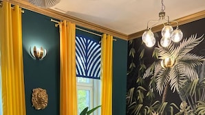 A room with a checkered floor, yellow curtains, a yellow sofa, and a tropical-themed wall mural. - Jungle Apartments II (Wroclaw)