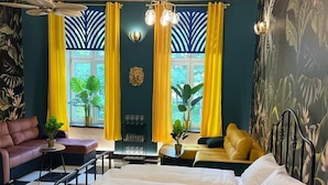 A bedroom with a bed, a sofa, a dining table, and a ceiling fan. - Jungle Apartments II (Wroclaw)