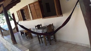 A hammock under a wooden pergola, a table with chairs, and a window with shutters. - pousada estrela matutina (Pirenópolis)