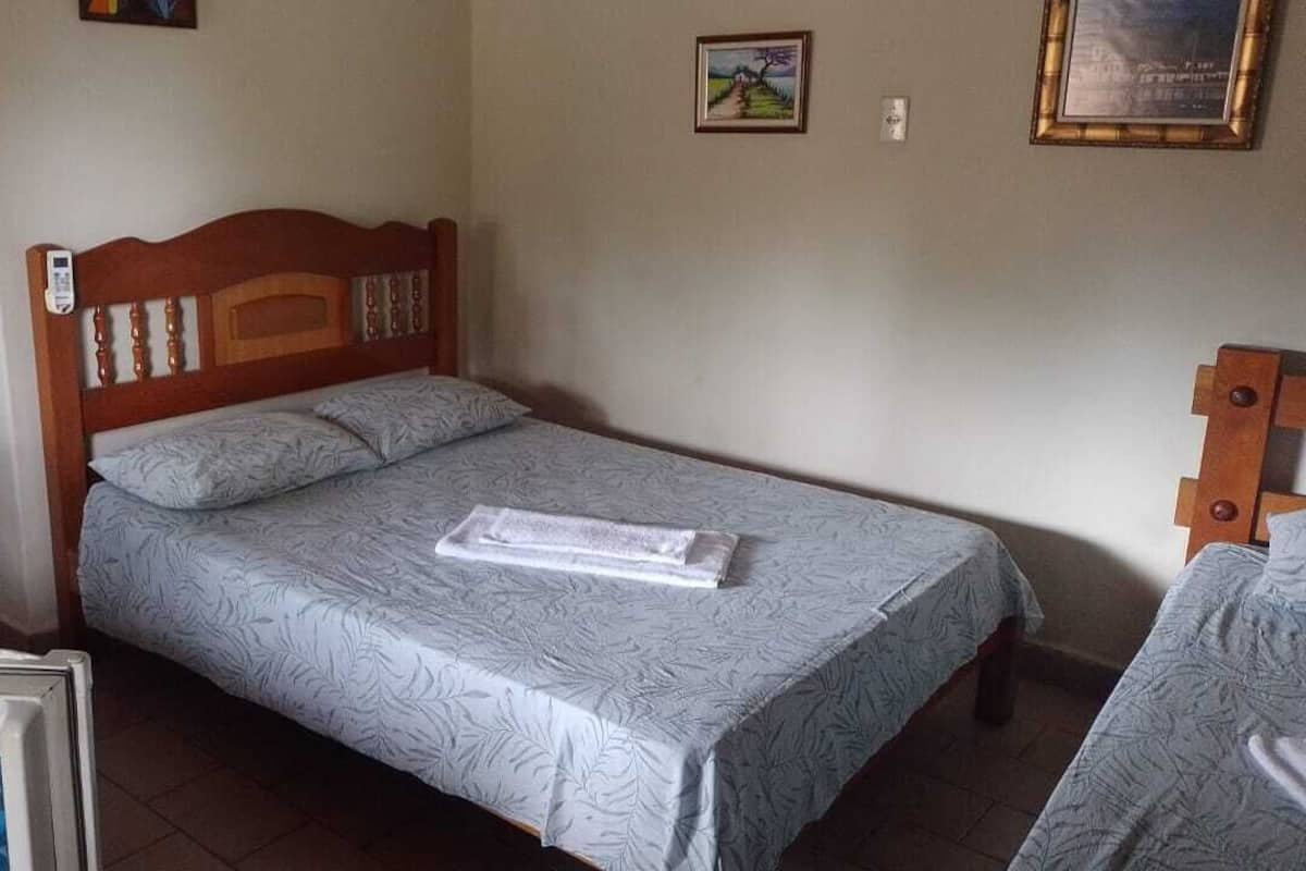 Ein Einzelbett mit Holz Kopfteil, einem Nachttisch und einem an der Wand befestigten Nachtlicht.