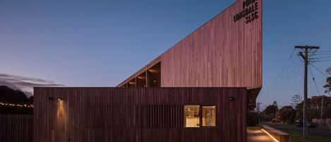 A modern wooden building with a sloped roof and a sign reading "POINT LONSDALE SLSC".