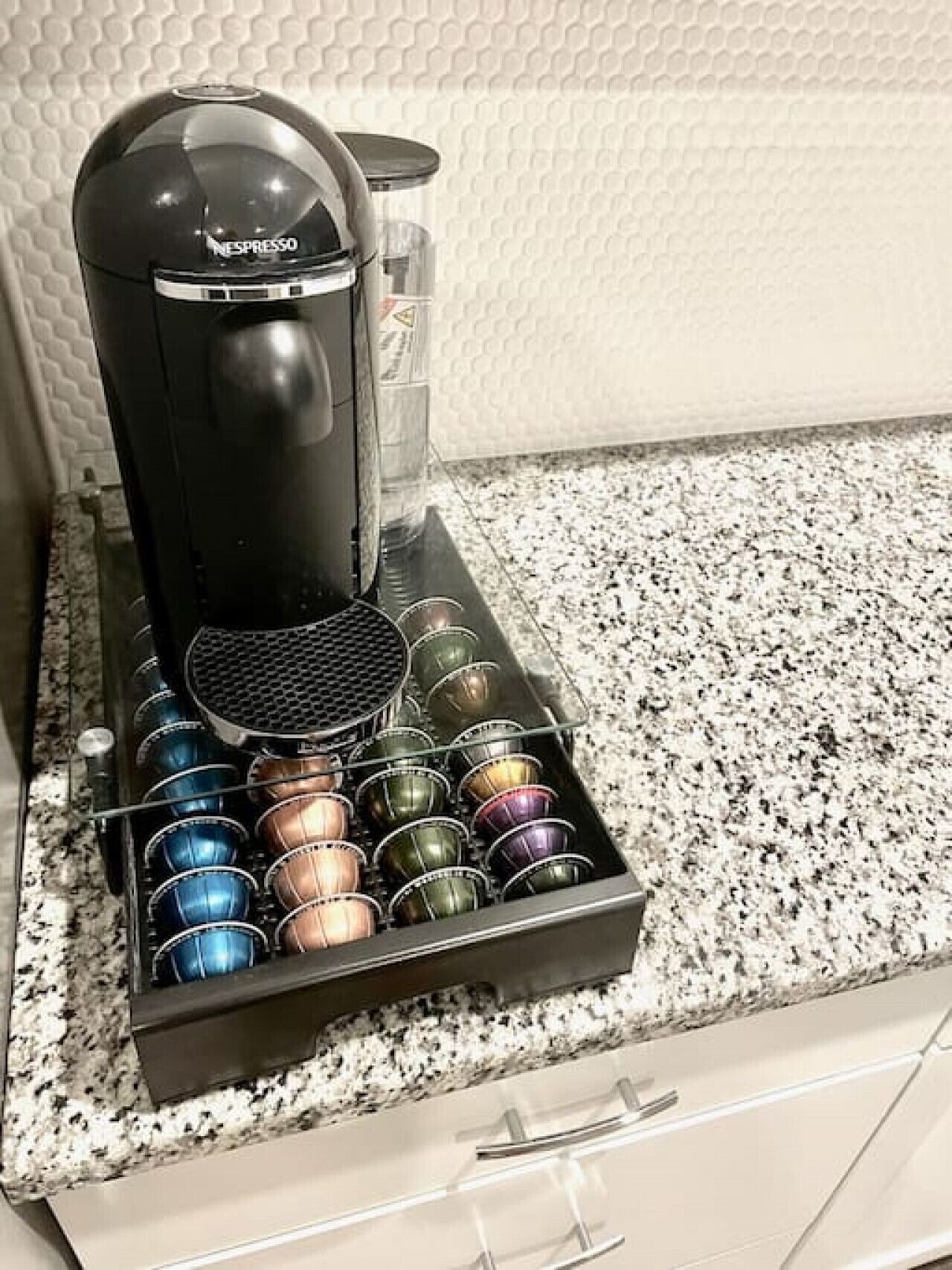 Een Nespresso koffieapparaat met een houder voor koffiekapsules op een aanrecht.