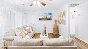A modern living room with a ceiling fan, a sofa, a coffee table, and decorative items.