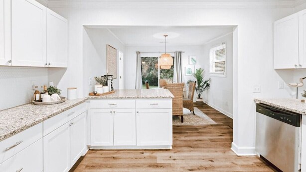 A modern kitchen with white cabinetry, granite countertops, and a wooden floor.