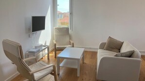 Ein modernes Wohnzimmer mit einer Couch, einem Sessel, einem Couchtisch und einem an der Wand befestigten Fernseher.