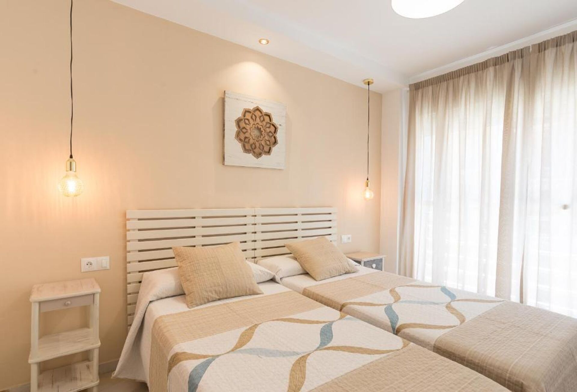 A double bed with a headboard, bedside tables, and a decorative wall piece.