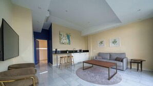 Un salon moderne avec un canapé, une table basse et des fauteuils. On y trouve également un coin cuisine équipé d’un évier et d’un plan de travail.