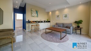 Un salon moderne avec un canapé, une table basse et un coin cuisine doté de tabourets de bar.