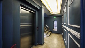A hallway with a closed elevator, a fire extinguisher, a staircase, and a mirror on the wall. - Royal Hotel-Kumkapi (Istanbul)