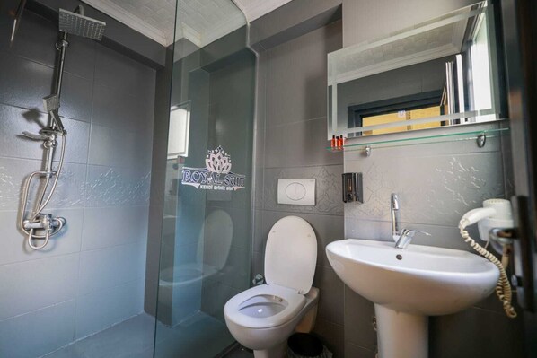 Un baño moderno con cabina de ducha de vidrio, inodoro y lavamanos.
