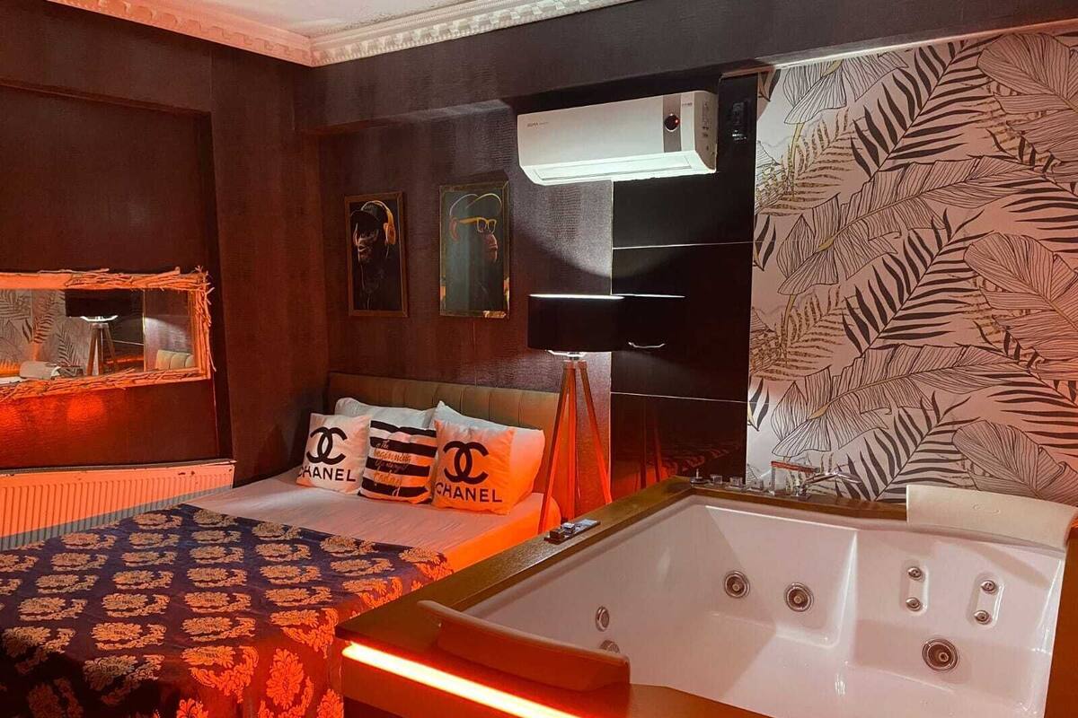 A bedroom with a large bed, a bedside table, a mirror, and a wall-mounted air conditioning unit.